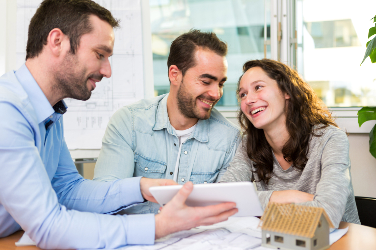 Young attractive couple signing contract with real estate agent
