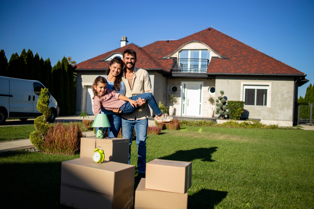 Portrait of cute couple holding their daughter in front of their new house